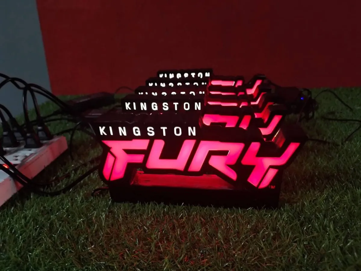 ป้ายอะคริลิคไฟ LED โลโก้ Kingston FURY สีแดงและขาววางเรียงกันบนพื้นหญ้าเทียม